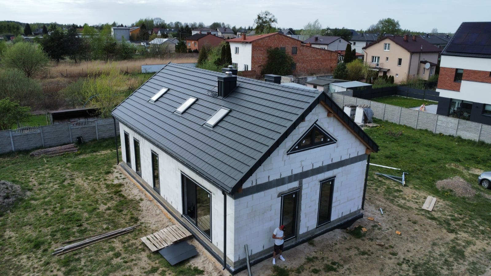 Dom z dachem z blachy na rąbek stojący i oknami dachowymi — widok z drona