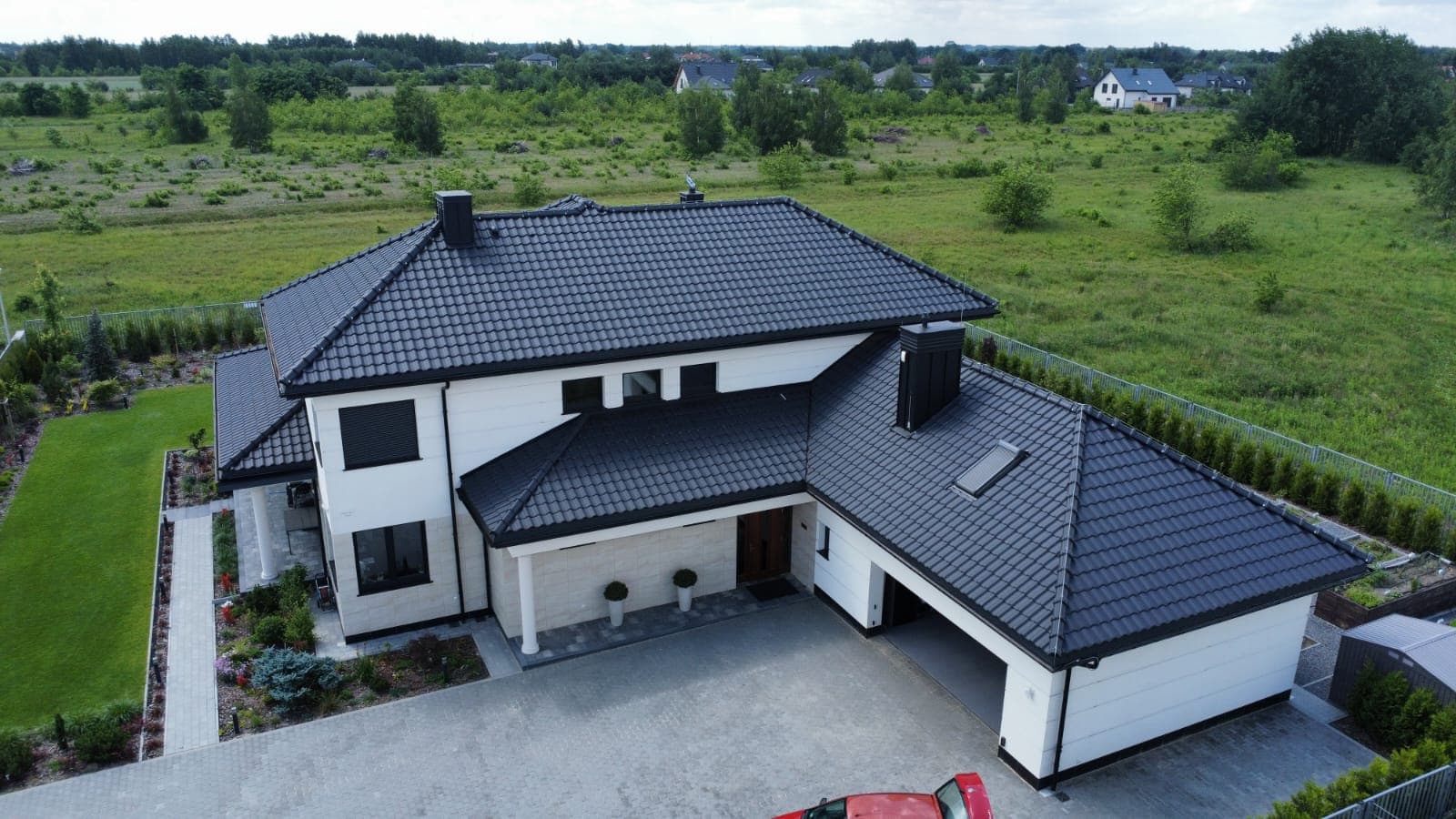 Dom z ciemną dachówką i garażem dwustanowiskowym — widok z drona