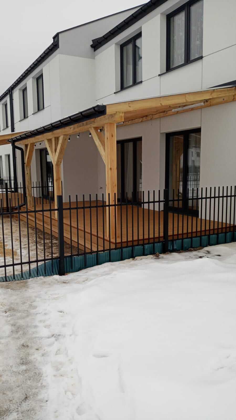 Drewniana pergola z pokryciem dachowym przy domu jednorodzinnym