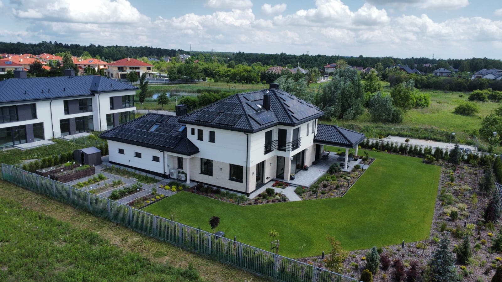 Rezydencja z czarną dachówką i panelami solarnymi — widok z drona